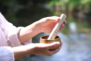 Woman with singing bowl in nature, closeup