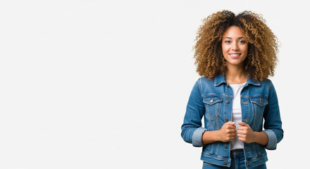 Young stylish latina woman student or model in denim jacket standing isolated on background looking at camera. Beautiful curly afro hair african american girl in trendy clothes smile with copy space