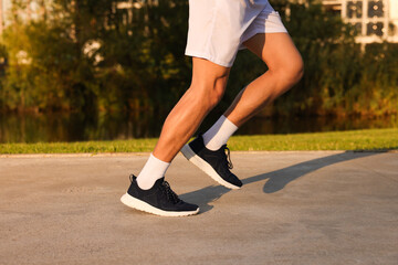 Fototapeta premium Man running near lake in park on sunny day, closeup