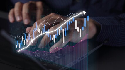 A business professional types on a laptop, with stock market graphs animated in the background, reflecting growth trends and financial analysis in a modern workspace. Copula