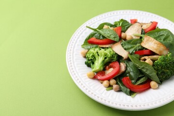 Tasty salad with eryngium mushrooms, chickpeas, vegetables and spinach on green background, closeup. Space for text