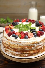 Delicious crepe cake with fresh berries on wooden table, closeup