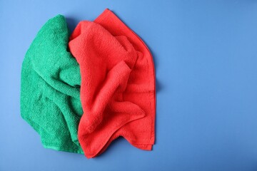 Bright terry towels on blue background, above view. Space for text