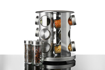 Set of spices in jars on table against white background