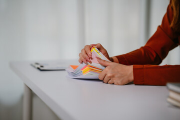 Young beautiful asian businesswoman holding unofficial spreadsheet paper accounting documents...