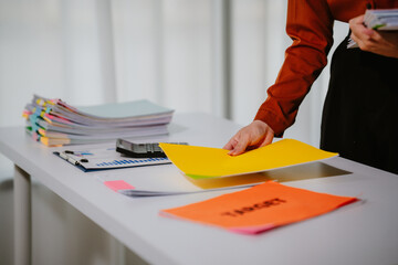 Young beautiful asian businesswoman holding unofficial spreadsheet paper accounting documents...