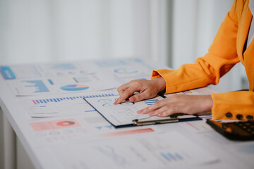 Young beautiful asian businesswoman holding unofficial spreadsheet paper accounting documents...