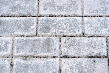 Close up of paving stones with salt deposits used for ice prevention in winter, white stains texture and residue from heavy road treatment chemicals