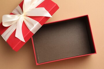 Opened gift box with beautiful lid on beige background, top view