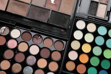 Different used eyeshadow palettes as background, closeup