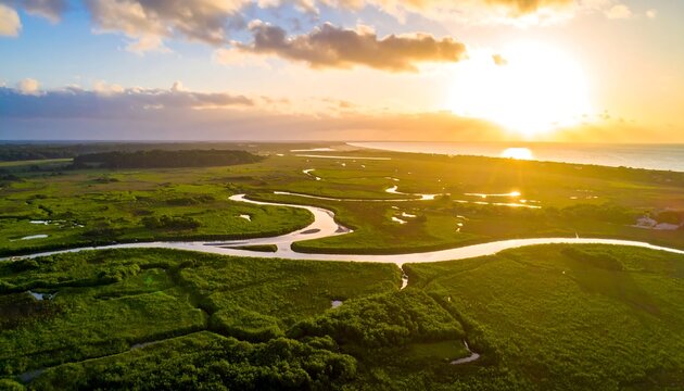 Aerial view of a winding river flowing through a lush green landscape at sunset