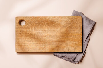 Empty cutting board on a beige background with leaf shadows