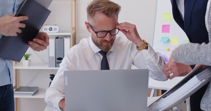 Busy man very tired and burned out because of much office work. Businessman stressed by business calls and bureaucratic workload. Team of employees pestering entrepreneur with lots of paperwork