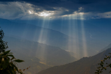 Sun rays coming out of cloud burst - at Rabangla, Sikkim, India. Slihoutte trees in foreground and...