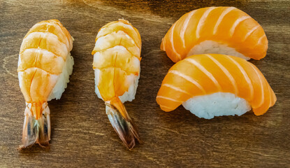 Three pieces of sushi with a shrimp tail on the left