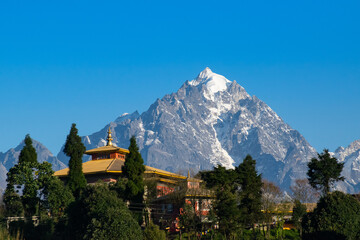 Beautiful light from sunrise on snow peak of Mount Siniolchu, one of the tallest mountains of the Indian state of Sikkim. 6,888 metres (22,598 ft). Ravangala monastery in foreground. Sikkim, India.
