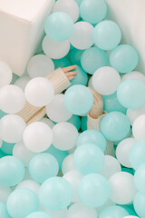 Children playing joyfully in a ball pit filled with aqua and white balls at a fun indoor play area