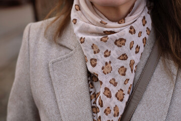 Stylish Beige Coat with Leopard Print Scarf and Minimalist Details. Close-up view of a chic beige coat complemented by trendy leopard print scarf, the neutral tones and elegant style