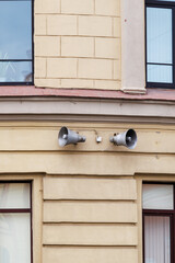 Two external loudspeakers are installed on wall of building to alert public in case of danger. Air raid warning.