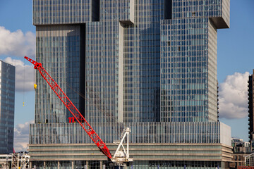 Modern skyscraper with reflective glass facade, featuring a red construction crane in front, showcasing urban development and architectural innovation in a vibrant cityscape