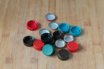 A bunch of bottle caps are on a wooden table