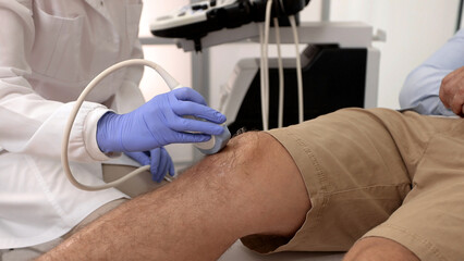 Sonography of knee joint. Male patient with knee injury during knee ultrasound with professional sonographer