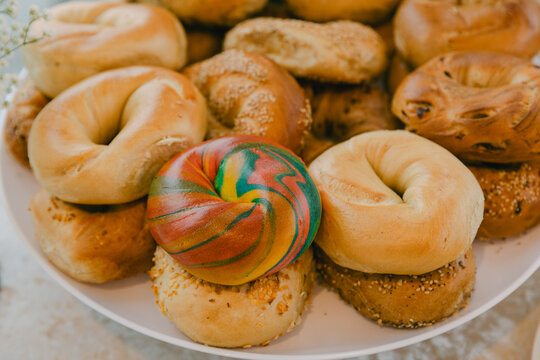 Colorful swirl bagel stands out among a variety of fresh bagels on a platter at a brunch gathering in a cozy cafe setting - Powered by Adobe