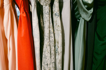 Colorful collection of dresses hanging in a boutique showcasing various styles and fabrics during a sunny day