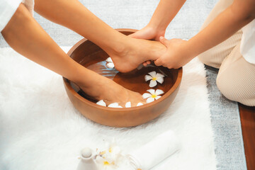 Woman indulges in blissful foot massage at luxurious spa salon while masseur give reflexology therapy in gentle day light ambiance resort or hotel foot spa. Quiescent