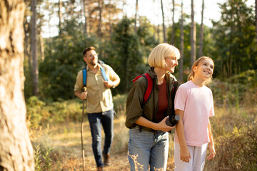 Family enjoys a hike in a forested area during a sunny afternoon with trees and nature surrounding them