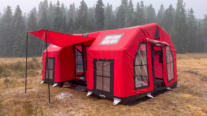 Vibrant Red Inflatable Camping Tent in a Rainy Forest Meadow