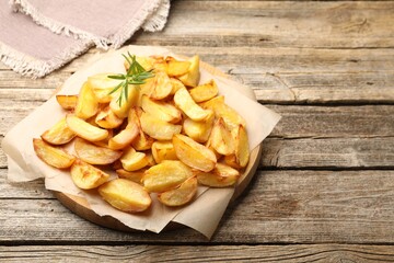 Tasty baked potatoes with rosemary on wooden table. Space for text