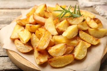 Tasty baked potatoes with rosemary on wooden table, closeup