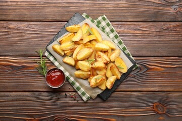 Tasty baked potatoes with rosemary, peppercorns and ketchup on wooden table, flat lay
