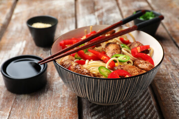 Delicious noodles with meat and vegetables served on wooden table, closeup