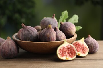 Fresh ripe figs in bowl on wooden table outdoors, closeup