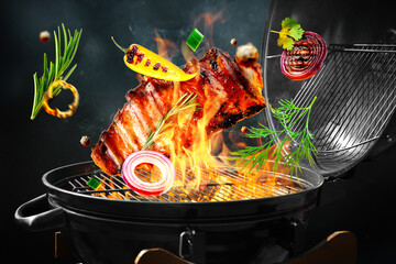 Ribs and vegetables flying above barbecue grill against dark background