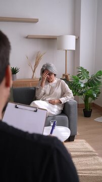 Senior woman talking to psychologist taking notes on clipboard