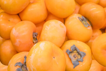 Background image: fresh ripe juicy persimmon fruits of the new harvest.