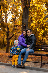 Fototapeta premium Happy family sitting on a park bench in autumn. autumn concept, autumn season, fall