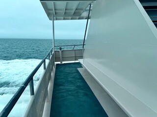 Minimal cruise deck with empty bench and railing over open sea, clean lines and negative space suited for a hero banner or website header