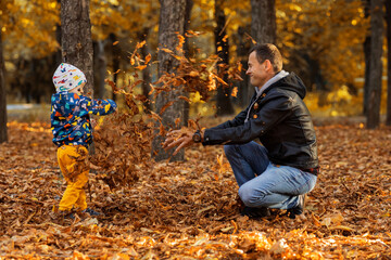 Happy father playing with his son in an autumn park. autumn concept, autumn season, fall