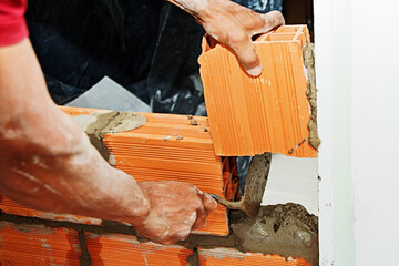 Bricklayer raising a brick wall by mason, Brasilia, Brazil, Sep. 2020