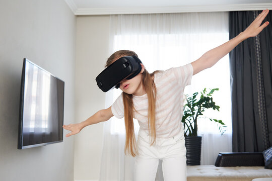 Teenage girl wearing virtual reality goggles headset and playing, vr box. technology, new generation, progress concept. Girl trying to touch objects in virtual reality.