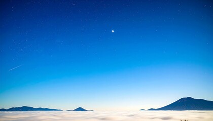 Vast expanse of a clear night sky above a sea of clouds, with distant mountains