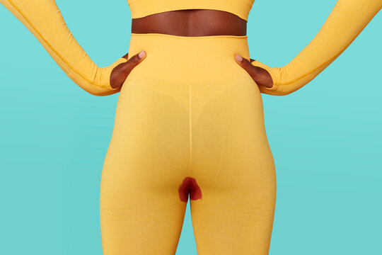 Woman in yellow workout clothes with period leak against blue