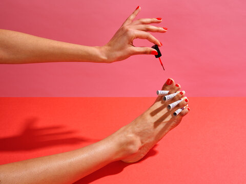 Woman painting red toenails with &pound;20 notes as toe separators