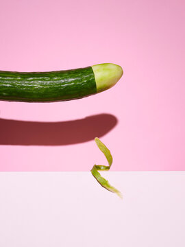 Cucumber with the tip peeled against pink background 
