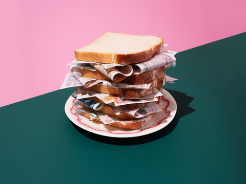 White bread sandwich with british pound notes filling on plate. 