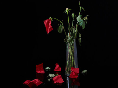 A bouquet of wilted red roses but the  roses are red flags